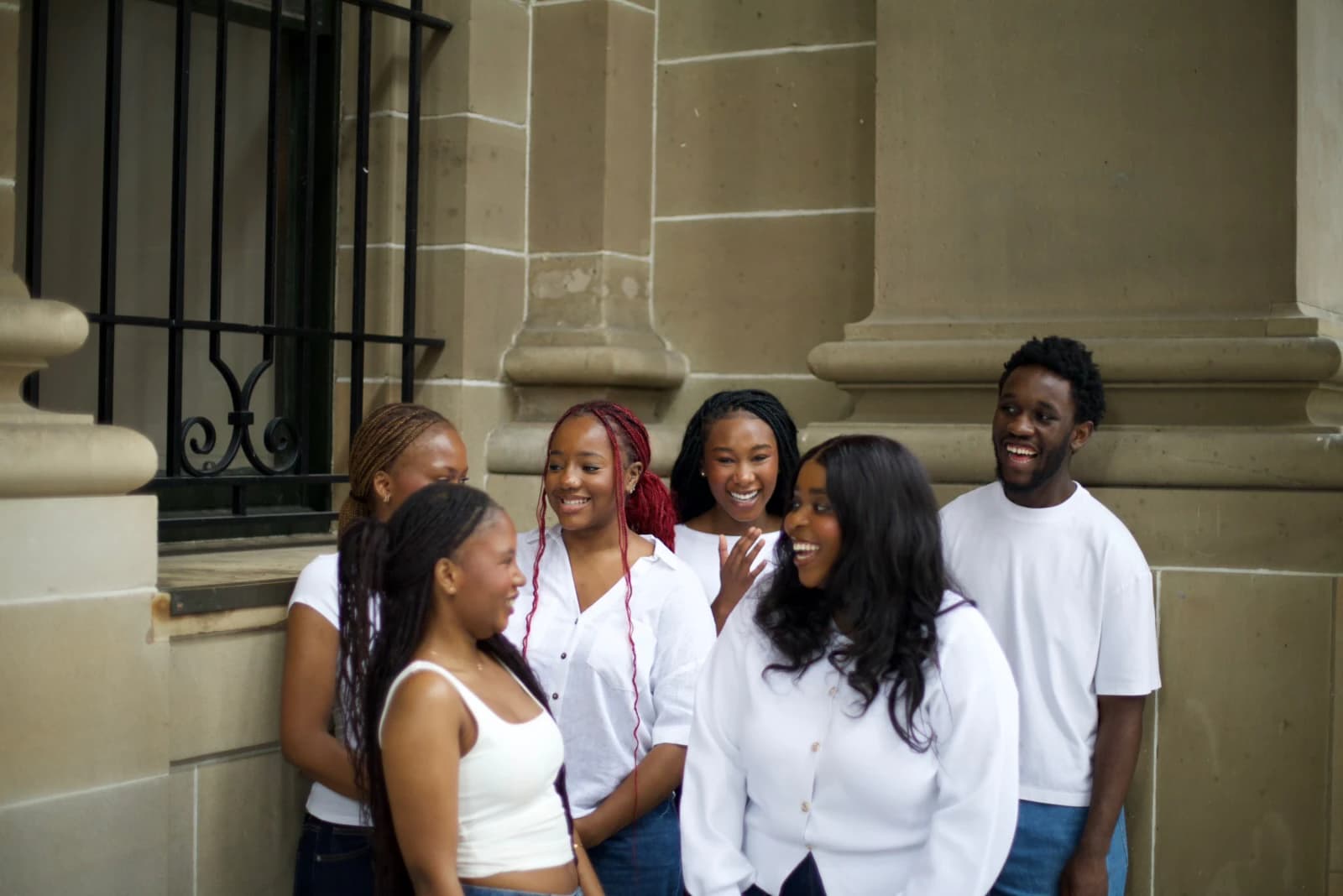 Six CREW'D UP team members laughing together outside a stone building.
